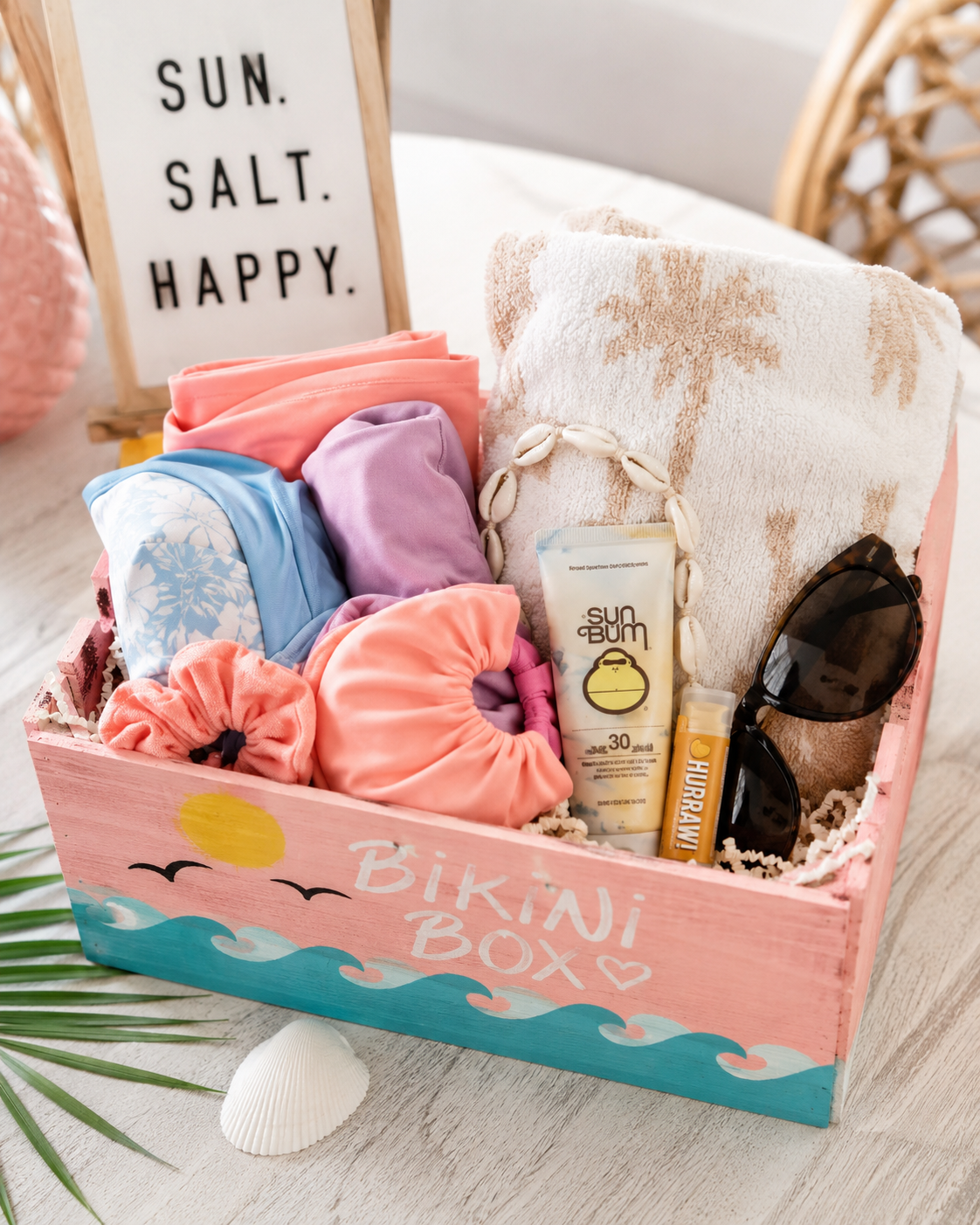 DIY bikini box styled as a summer gift basket with swimwear, sunscreen, towel, and beach accessories.
