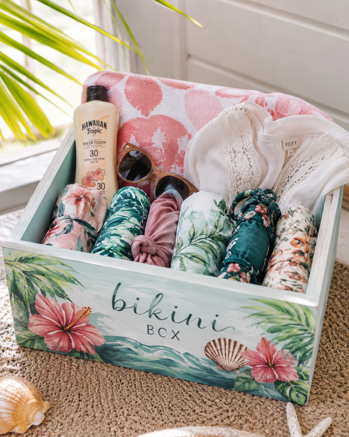 Finished bikini box filled with bikinis, beach towels, sunscreen, sunglasses, and summer accessories.
